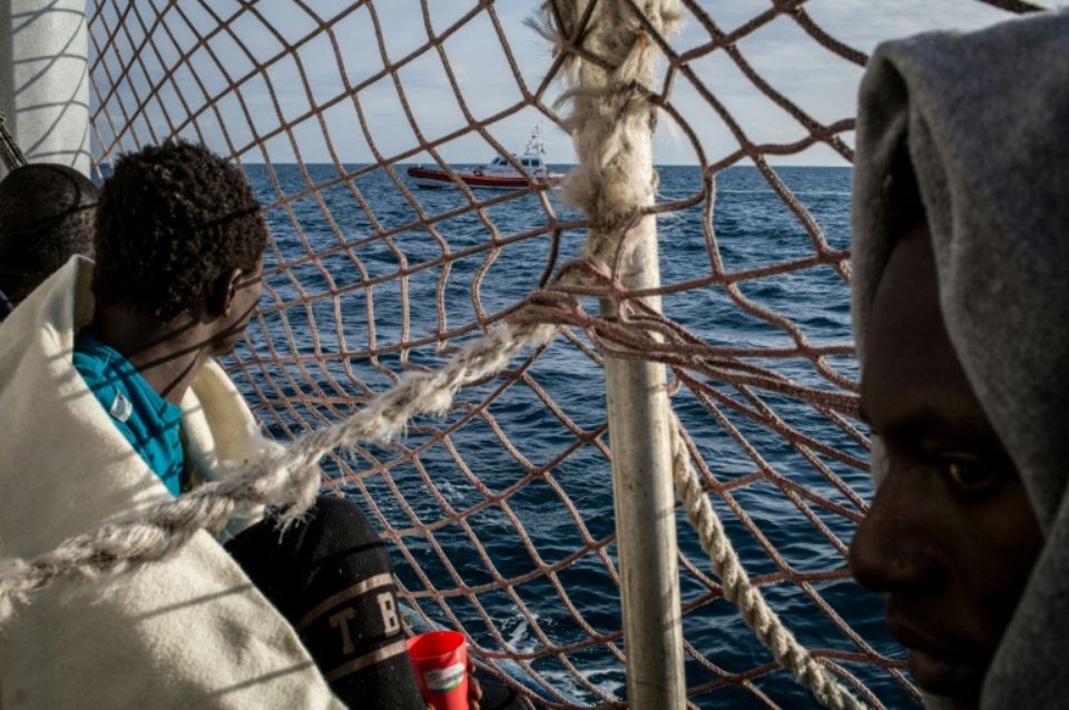 Des migrants à bord du Sea Watch 3 observent un bateau des garde-côtes italiens