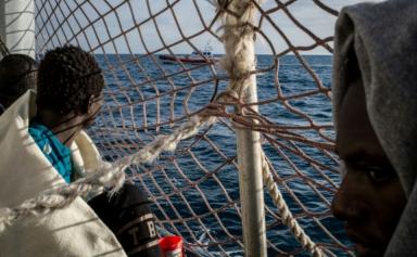 Des migrants à bord du Sea Watch 3 observent un bateau des garde-côtes italiens